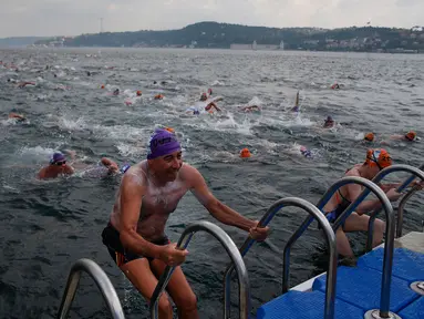 Atlet keluar dari air setelah mengikuti lomba renang dari Asia hingga Eropa di Selat Bosphorus ke-30, Istanbul, Turki, (22/7). Lebih dari 2.000 peserta terjun dari feri dan berenang sejauh sekitar 6,5 km di acara tersebut. (AP Photo/Lefteris Pitarakis)