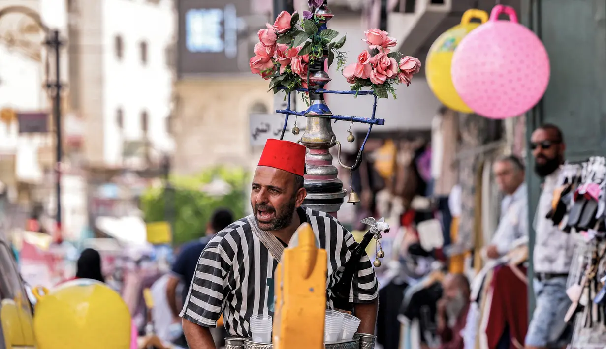 Seorang pedagang kaki lima jus segar Palestina memanggil pelanggan di sebuah pasar di kota tua Betlehem di Tepi Barat yang diduduki (14/9/2021).  Ekonomi Palestina diperkirakan akan tumbuh empat persen pada tahun 2021 setelah terpukul pada tahun 2020 akibat pandemi COVID-19. (AFP/Emmanuel Dunand)