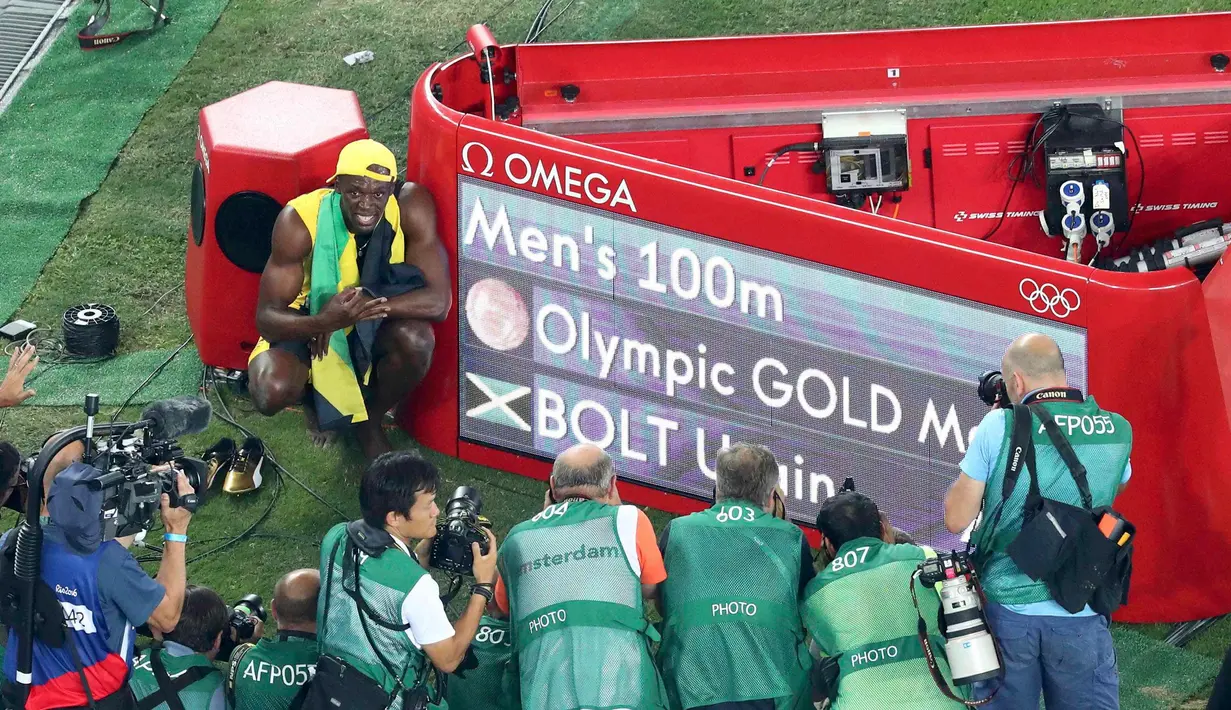 Usain Bolt berselebrasi di samping papan skor kemenangan dirinya meraih emas kategori sprint 100 meter Olimpiade 2016 di Rio de Janeiro, Brasil, (15/8). Usain Bolt berhasil meraih emas di tiga Olimpiade berturut-turut. (REUTERS/Fabrizio Bensch)