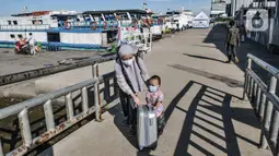 Seorang ibu dan anaknya mendorong koper bawaannya saat tiba di Dermaga Kali Adem, Muara Angke, Jakarta, Minggu (27/12/2020). Sebanyak 3.018 wisatawan berkunjung ke Kepulauan Seribu seperti Pulau Tidung, Pari, dan Pramuka untuk mengisi libur Natal (merdeka.com/Iqbal Nugroho)