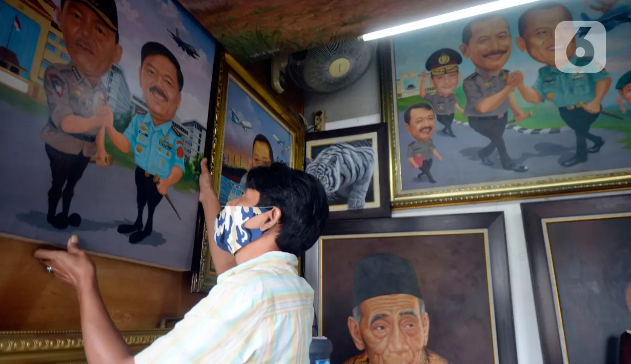Seorang pelukis memacang lukisan tokoh-tokoh nasional di Depan Pasar Baru, Jakarta, Kamis (24/12/2020). Para pelukis memasarkan lukisannnya dengan harga bervariasi dari dari Rp 500 ribu hingga Rp 2,5 juta. (merdeka.com/Dwi Narwoko)