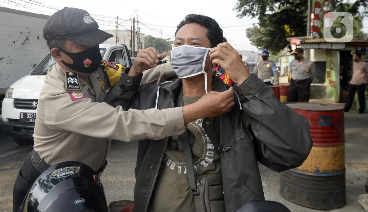 Anggota polisi dari Polsek Parung membantu memasangkan masker kepada pengendara sepeda motor di depan Polsek Parung, Kabupaten Bogor, Jawa Barat, Rabu (2/9/2020). Pembagian masker gratis setiap usai apel ini inisiatif anggota sejak masa pandemi COVID-19. (merdeka.com/Dwi Narwoko)
