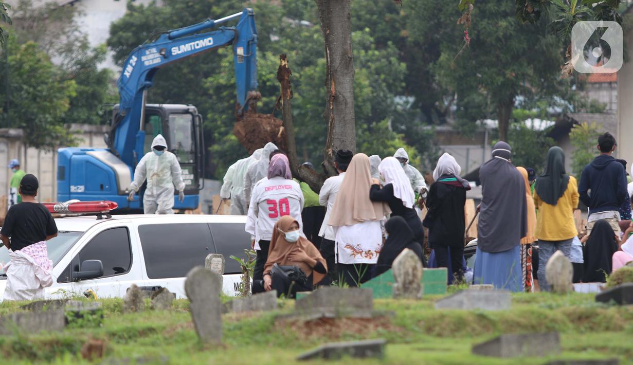 Keluarga dan kerabat menyaksikan pemakaman jenazah dengan protokol COVID-19 dari luar area di TPU Srengseng Sawah, Jakarta, Kamis (21/1/2021). Sebagian lahan TPU Srengseng Sawah yang dijadikan lokasi pemakaman jenazah Covid-19 kini hanya tersisa 79 petak makam. (Liputan6.com/Helmi Fithriansyah)