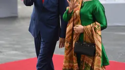 Presiden RI, Joko Widodo didamping Ibu Negara Iriana Widodo menyapa awak media saat tiba menghadiri KTT G20 di Hamburg, Jerman, (7/7). Sejumlah pemimpin negara berkumpul dalam KTT G20 pada 7-8 Juli 2017. (AFP Photo/Patrik Stollarz)