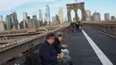 Orang-orang menikmati sarapan mereka di mana kaki langit Manhattan terlihat dari Jembatan Brooklyn, New York, 3 Desember 2018. Jembatan yang selesai dibangun tahun 1883 itu ditetapkan sebagai National Historic Landmark pada tahun 1964. (AP/Wong Maye-E)