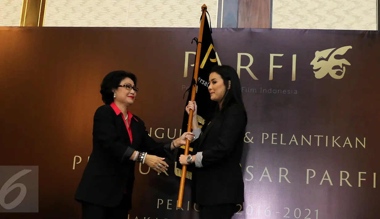 Ketua Dewan Pendiri, Debby Chintya Dewi memberikan bendera PARFI 56 kepada Ketua Umum Parfi 56, Marcella Zalianti pada acara pengukuhan dan pelantikan pengurus besar PARFI 56, Jakarta, Senin (24/10). (Liputan6.com/Herman Zakharia)