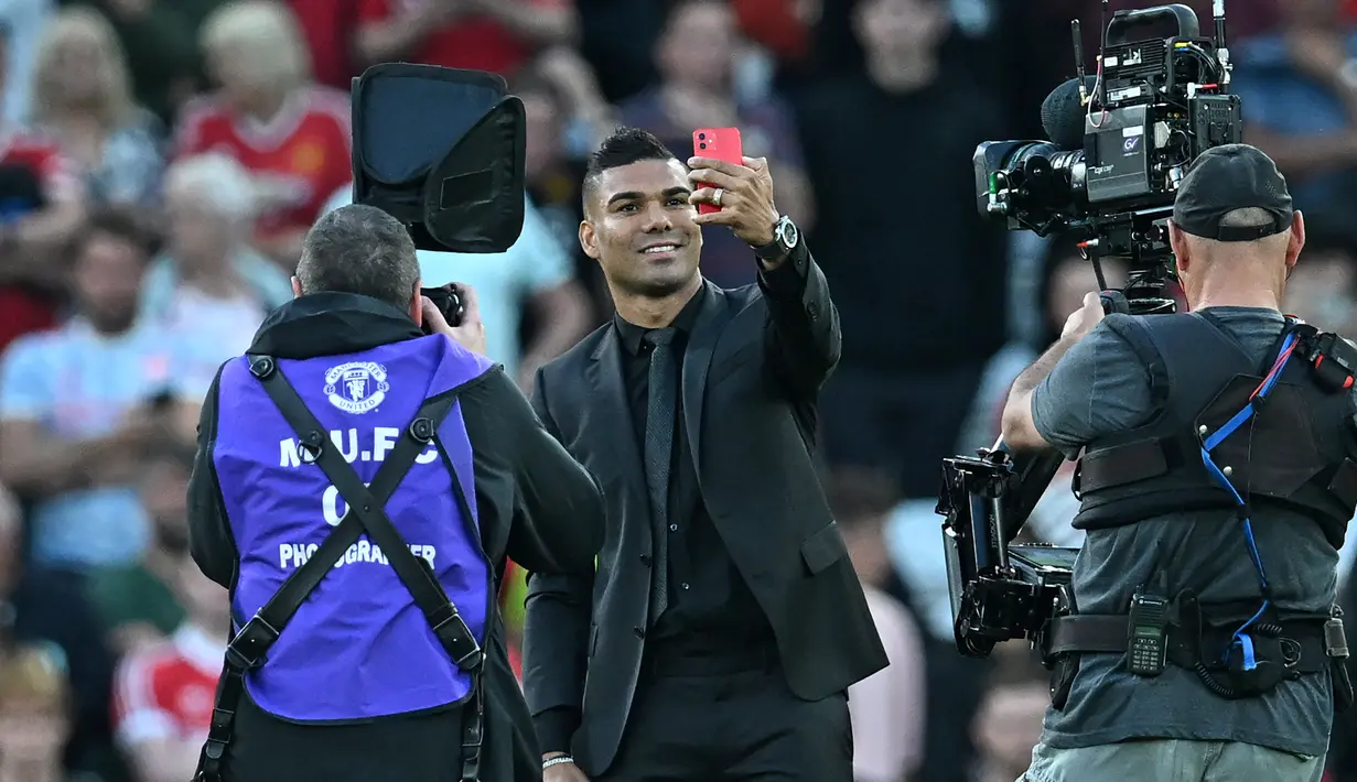 Gelandang Manchester United Casemiro berswafoto saat diperkenalkan kepada para pendukung sesaat sebelum laga MU vs Liverpool dimulai di stadion Old Trafford, Senin (22/8/2022). Pemain berusia 30 tahun ini dianggap sebagai salah satu gelandang bertahan terbaik di dunia. (Paul ELLIS / AFP)