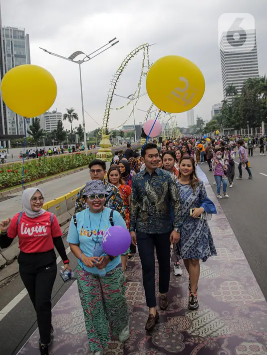 Sejumlah orang yang mengenakan batik berjalan di catwalk sepanjang Jalan Jenderal Sudirman, Jakarta, Minggu (2/10/2022). Kegiatan yang diikuti ratusan orang ini diselenggarakan oleh Bank Mandiri untuk menyambut Hari Batik Nasional yang jatuh setiap tanggal 2 Oktober 2022. (Liputan6.com/Faizal Fanani)