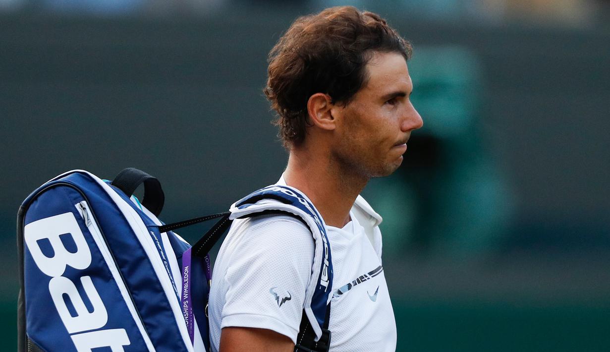 Petenis Spanyol, Rafael Nadal, saat akan meninggalkan lapangan setelah dikalahkan petenis Luksemburg, Giller Muller di perempat final Wimbledon 2017, Senin (10/7). Nadal menyerah dari Mueller usai melewati pertarungan lima set. (Adrian DENNIS/AFP)