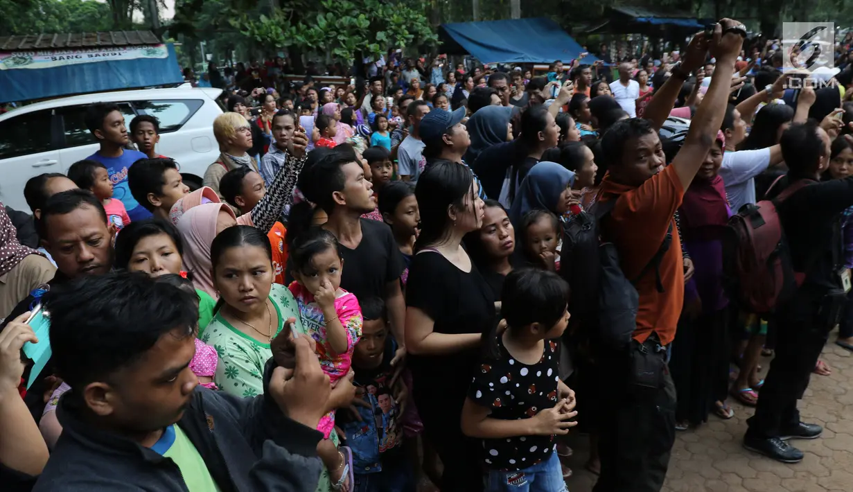 Sejumlah warga saat melihat pemakaman Julia Perez di Taman Pemakaman Umum Pondok Ranggon, Jakarta Timur, Sabtu (10/6). Jupe menghembuskan napas terakhir di RSCM, pada Sabtu 10 Juni 2017. (Liputan6.com/Herman Zakharia)
