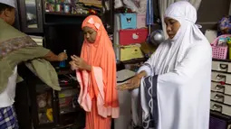 Keluarga Muslim Thailand menggunakan cairan desinfektan sebelum berdoa di ruang tamu rumah mereka di Bangkok, 28 April 2020. Banyak tempat ibadah ditutup guna membendung penyebaran Virus Corona COVID-19 ketika Umat Muslim di seluruh dunia menyambut bulan suci Ramadan. (AP Photo/Gemunu Amarasinghe)