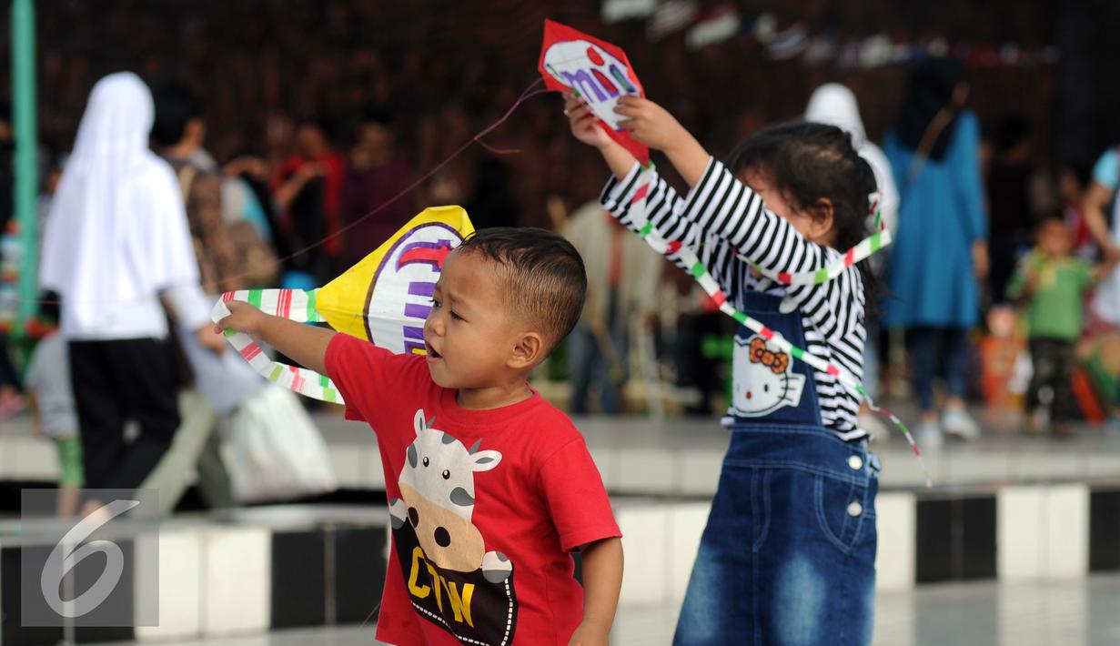 Dua orang anak berusaha menerbangkan layang layang saat bermain di Lapangan Monumen Tugu Pancasila TMII, Jakarta, Jumat (8/7). TMII masih menjadi lokasi favorit warga menghabiskan libur hari raya. (Liputan6.com/Helmi Fithriansyah)