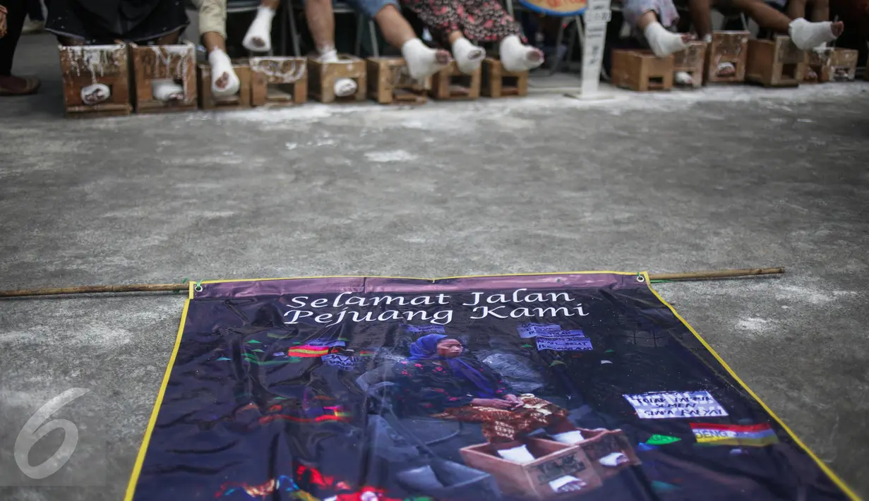 Poster mengenang meninggalnya peserta aksi semen kaki bernama Patmi (48), di depan Istana Merdeka, Jakarta, Rabu (22/3). Delapan aktivis menggelar aksi semen kaki untuk menghormati dan melanjutkan perjuangan Ibu Patmi (Liputan6.com/Faizal Fanani)