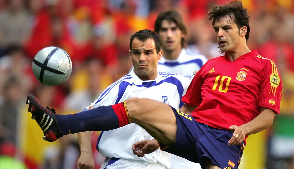 Striker Timnas Spanyol, Fernando Morientes mengontrol bola di depan bek Yunani, Mihalis Kapsis pada laga fase Grup A Euro 2004 di Bessa Stadium, Porto, Portugal (16/6/2004). Hingga pensiun pada Juli 2015, Fernando Morientes total tampil dalam 47 laga bersama Timnas Spanyol dengan torehan 27 gol dan 2 assist. Pada laga debutnya menghadapi Swedia (25/3/1998) jelang Piala Dunia 1998, ia langsung mencetak dua gol untuk membawa Spanyol menang 4-0. (AFP/Javier Soriano)