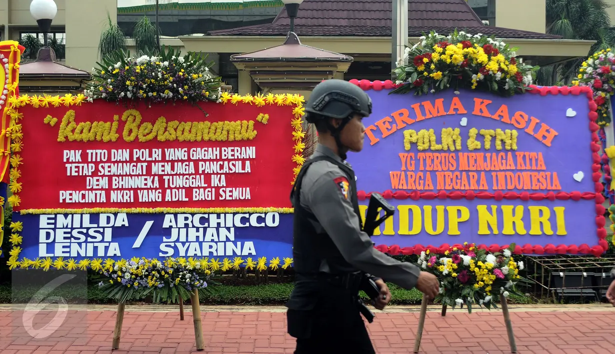 Petugas melintasi deretan karangan bunga yang diletakkan di depan Mabes Polri, Jakarta, Rabu (3/5). Ratusan karangan bunga itu terus berdatangan dan mengelilingi gedung Mabes Polri di Jalan Trunojoyo Jakarta Selatan. (Liputan6.com/Helmi Fithriansyah)