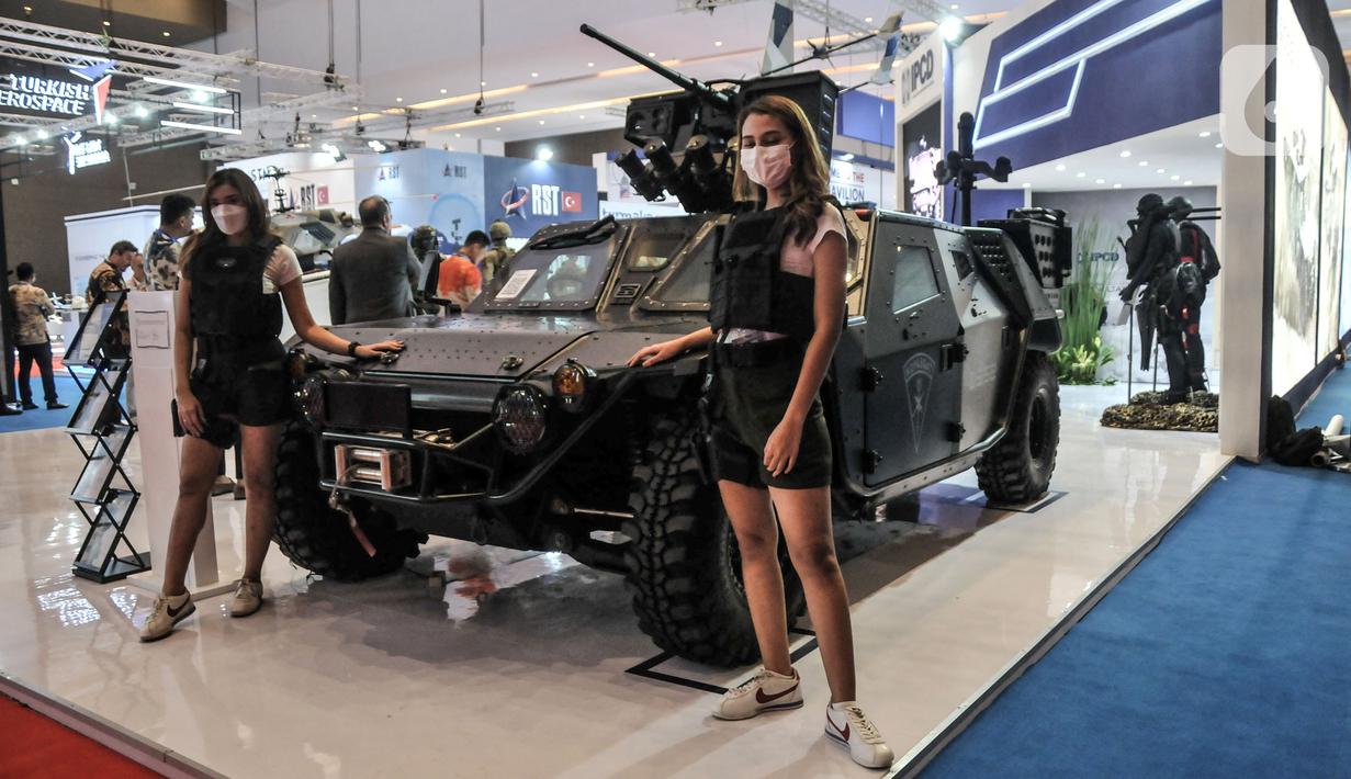 Sales Promotion Girl (SPG) berpose di depan kendaraan tempur yang dipamerkan dalam Indo Defence 2022 Expo & Forum di JIExpo, Kemayoran, Jakarta, Rabu (2/11/2022). Kementerian Pertahanan bersama PT Napindo Media Ashatama menggelar pameran industri pertahanan terbesar se-Asia Tenggara bertemakan “Peace, Prosperity, Strong Defence” yang diikuti 905 perusahaan dari 59 negara dan berlangsung hingga 5 November mendatang. (merdeka.com/Iqbal S. Nugroho)