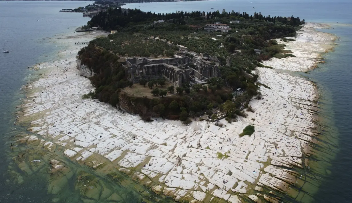 Pemandangan semenanjung Sirmione, di danau Garda, Italia, Jumat (12/8/2022). Permukaan air Danau Garda telah turun secara kritis menyusul kekeringan parah yang mengakibatkan munculnya bebatuan di sekitar Semenanjung Sirmione. (AP Photo/Antonio Calanni)