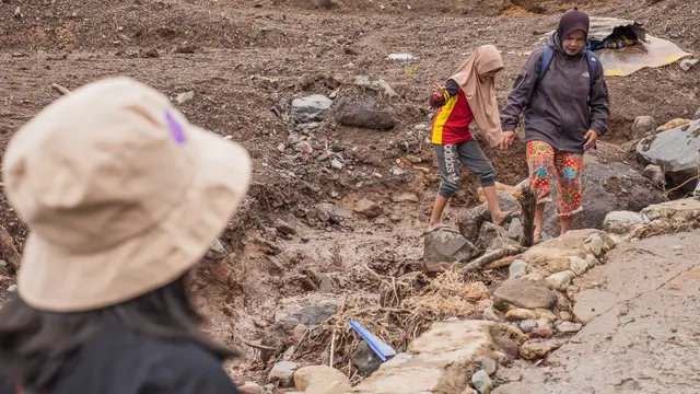 Korban banjir melintas di atas tumpukan material sisa banjir Sumbar. (Liputan6.com)