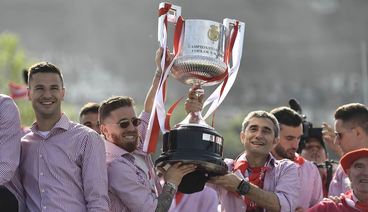 Pelatih Athletic Bilbao, Ernesto Valverde dan Iker Muniain, mengangkat trofi saat melakukan pawai perayaan juara Copa del Rey dengan menyusuri Sungai Nervion, Bilbao, Jumat (12/4/2024). (AP Photo/Alvaro Barrientos)