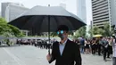 Seorang pengacara membawa payung dan mengenakan topeng saat berdemonstrasi di Hong Kong, Rabu (7/8/2019). Para pengacara Hong Kong telah dua kali terlibat dalam aksi protes terhadap RUU Ekstradisi. (AP Photo/Kin Cheung)
