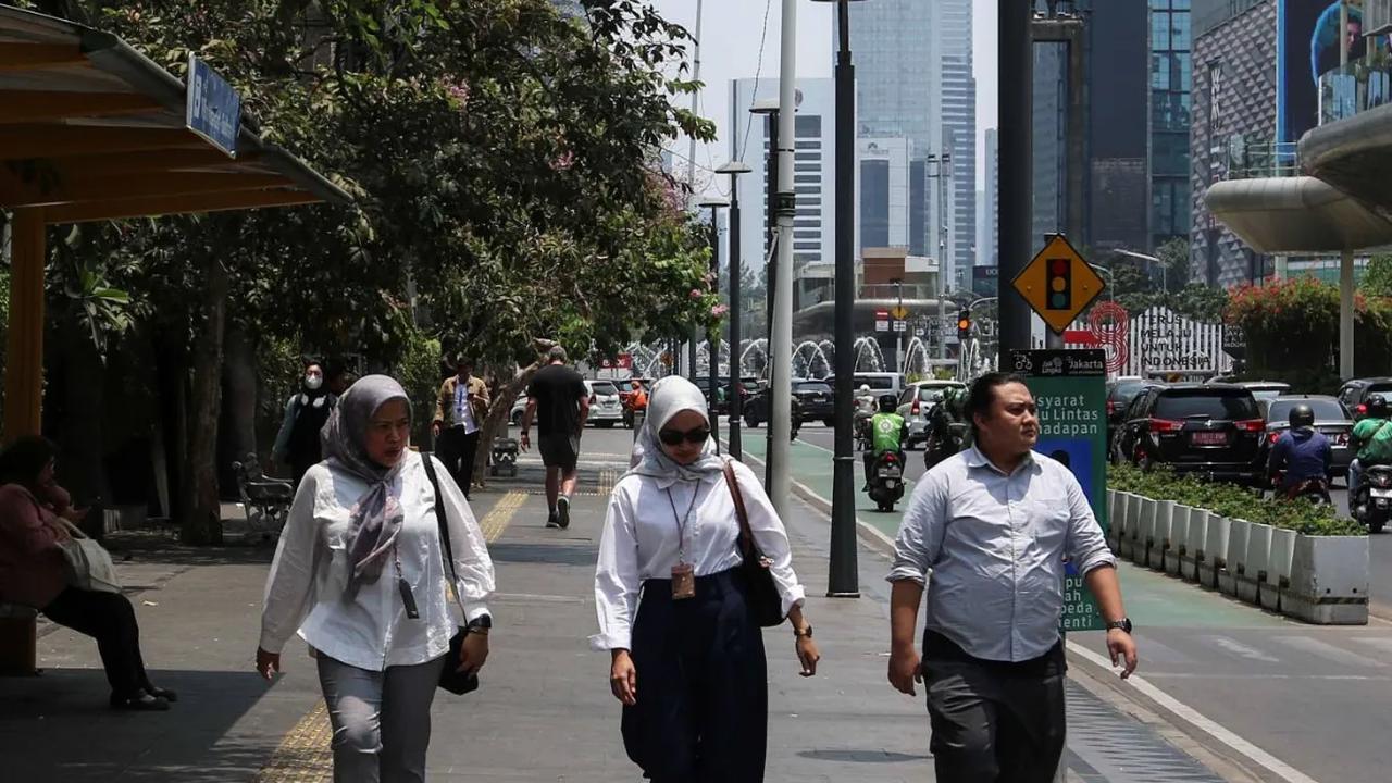 Pekerja berjalan di trotoar di kawasan Jakarta saat fenomena Kulminasi Utama atau Hari Tanpa Bayangan pada Senin (9/10/2023) siang.
