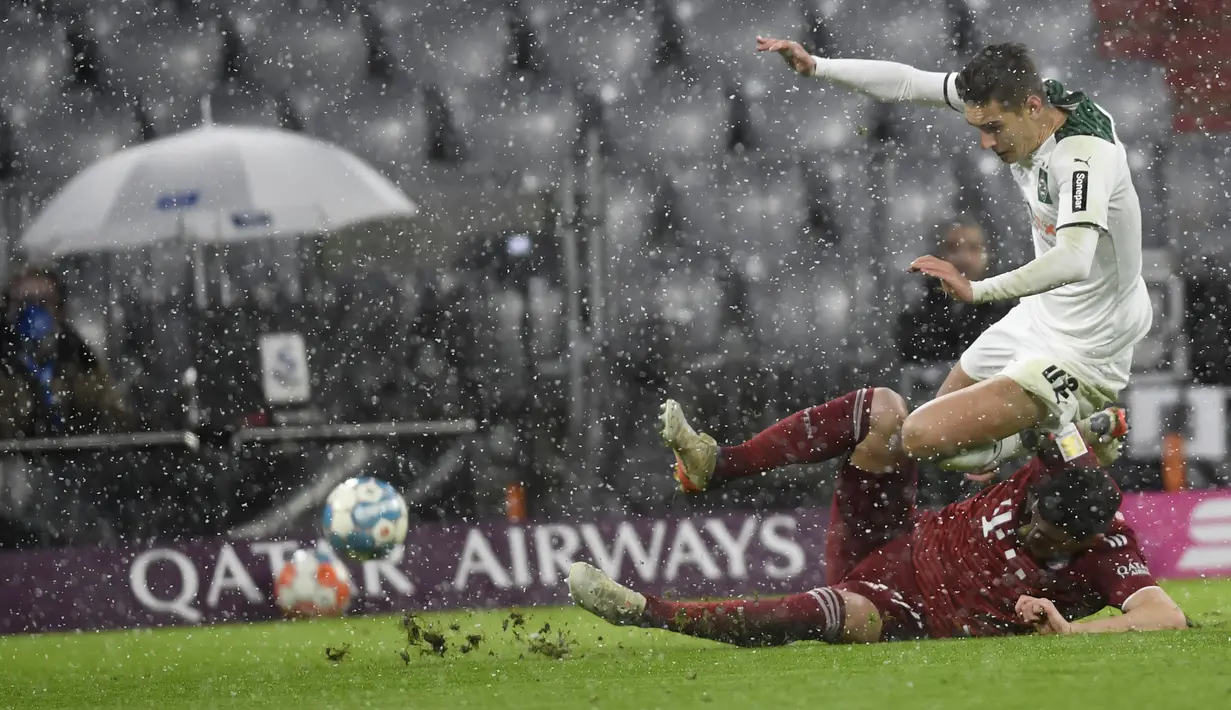 Bek Bayern Munchen Benjamin Pavard berebut bola dengan gelandang Borussia Monchengladbach, Florian Neuhaus (atas) pada laga pekan ke-18 Bundesliga di Allianz Arena, Sabtu (8/1/2022) dini hari WIB. Bayern Munchen dipermalukan di kandang sendiri 1-2. (AP Photo/Andreas Schaad)