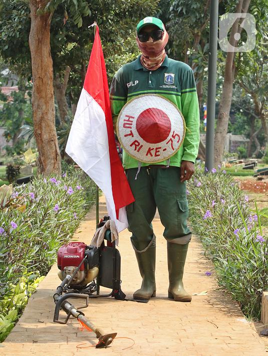 Petugas Pertamanan dan Kehutanan Kota Jakarta Pusat Darwanto mengenakan atribut kemerdekaan berpose usai memotong rumput di TPU Karet Bivak, Jakarta, Minggu (16/8/2020). Para petugas bekerja dengan mengenakan atribut kemerdekaan dalam rangka menyambut HUT ke-75 RI. (Liputan6.com/Herman Zakharia)