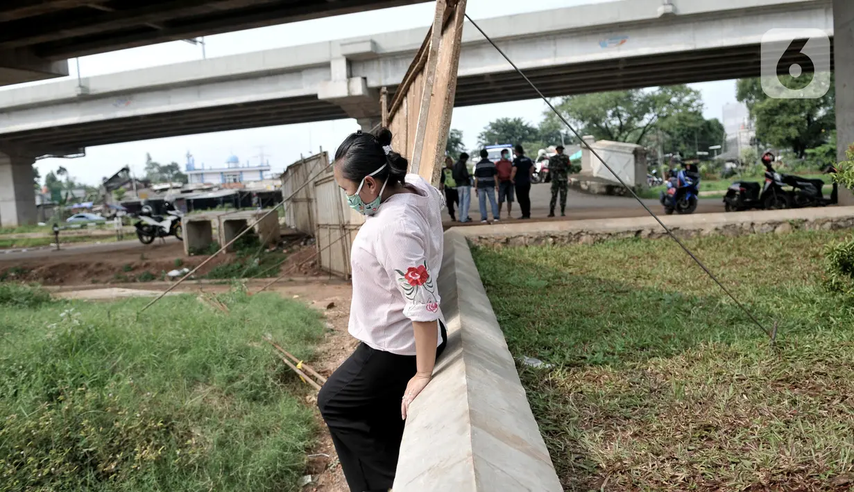 Warga berusaha melintasi pagar pembatas yang menutup akses menuju kawasan Cipinang Melayu, Jakarta, Minggu (29/3/2020). Warga membatasi aktivitas pengunjung yang melintasi kawasan mereka dengan menutup sebagian jalan dengan seng guna mengantisipasi penyebaran corona. (merdeka.com/Iqbal Nugroho)