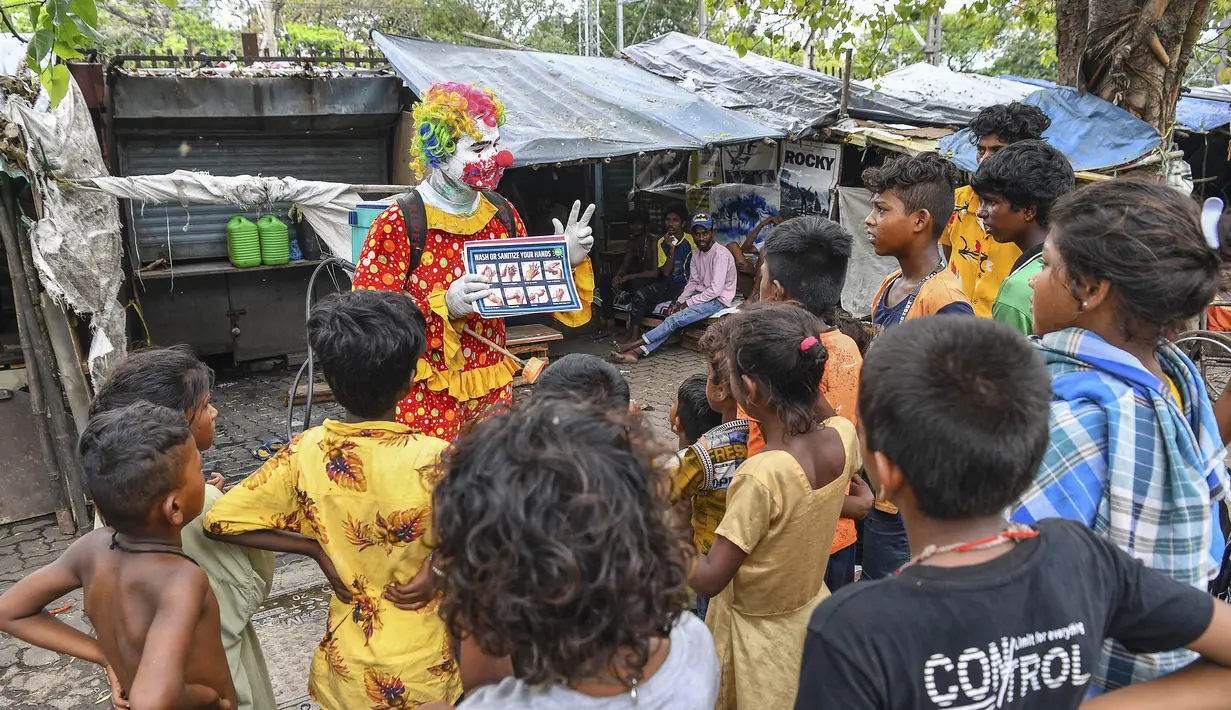 Relawan pekerja sosial, Ashok Kurmi mengajarkan anak-anak cara mengikuti protokol kesehatan di daerah kumuh Mumbai pada 2 Juni 2021. Kurmi turun tangan memerangi virus Corona COVID-19 di daerah kumuh Mumbai menggunakan aksesori yang tidak biasa, yaitu kostum badut. (INDRANIL MUKHERJEE/AFP)
