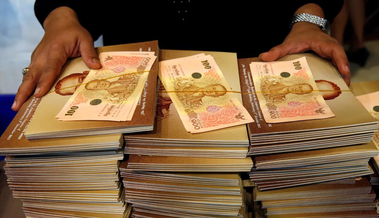 Pegawai bank menunjukan uang kertas 100 baht edisi ulang tahun Raja Thailand Bhumibol Adulyadej ke-84 di kantor pusat Bank Tabungan Pemerintah di Bangkok, Thailand (18/10). (Reuters/Edgar Su)