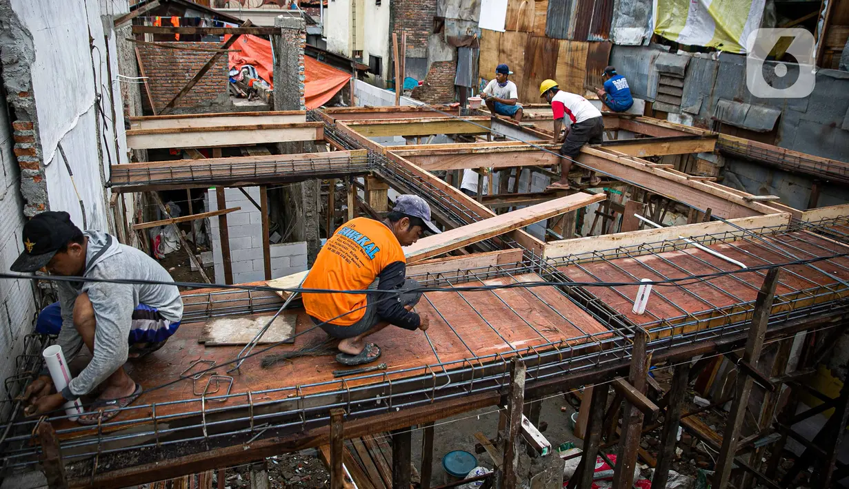 Para pekerja menyelesaikan pembangunan rumah panggung di dekat bantaran Kali Ciliwung, Kampung Melayu, Jakarta, Rabu (7/4/2021). Pemerintah Provinsi DKI Jakarta melakukan renovasi terhadap 40 hunian warga Kampung Melayu menjadi rumah panggung. (Liputan6.com/Faizal Fanani)