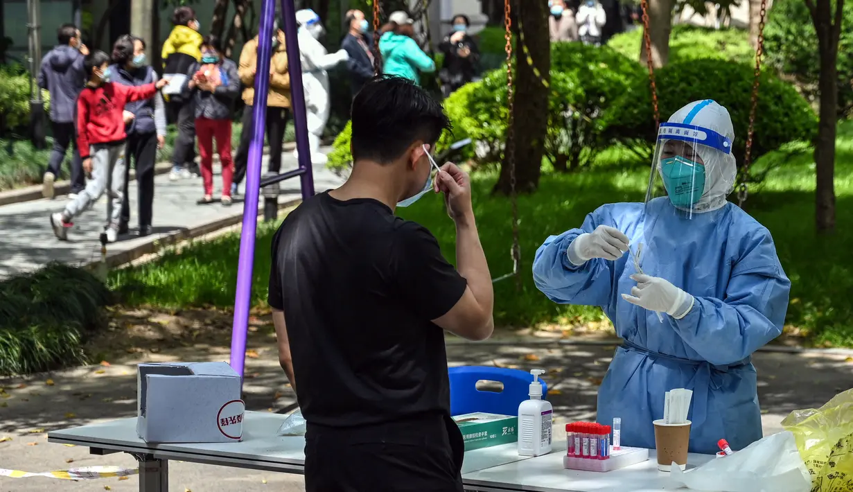 Seorang petugas kesehatan bersiap untuk melakukan tes swab COVID-19 di kompleks perumahan saat lockdown tahap kedua di Distrik Jing'an, Shanghai, China, Rabu (6/4/2022). (HECTOR RETAMAL/AFP)