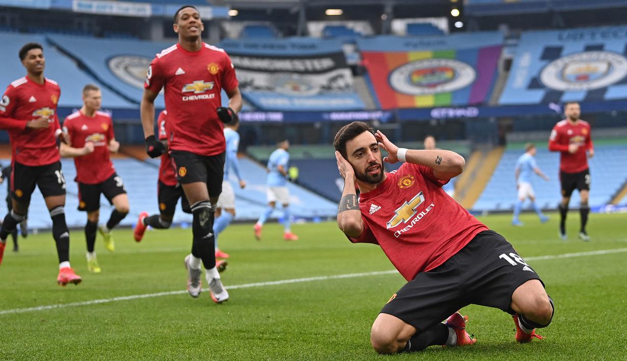 Gelandang Manchester United, Bruno Fernandes (depan) melakukan selebrasi usai mencetak gol pertama timnya ke gawang Manchester City melalui eksekusi penalti dalam laga lanjutan Liga Inggris 2020/21 di Etihad Stadium, Minggu (7/3/2021). MU menang 2-0 atas Mancity. (AFP/Laurence Griffiths/Pool)