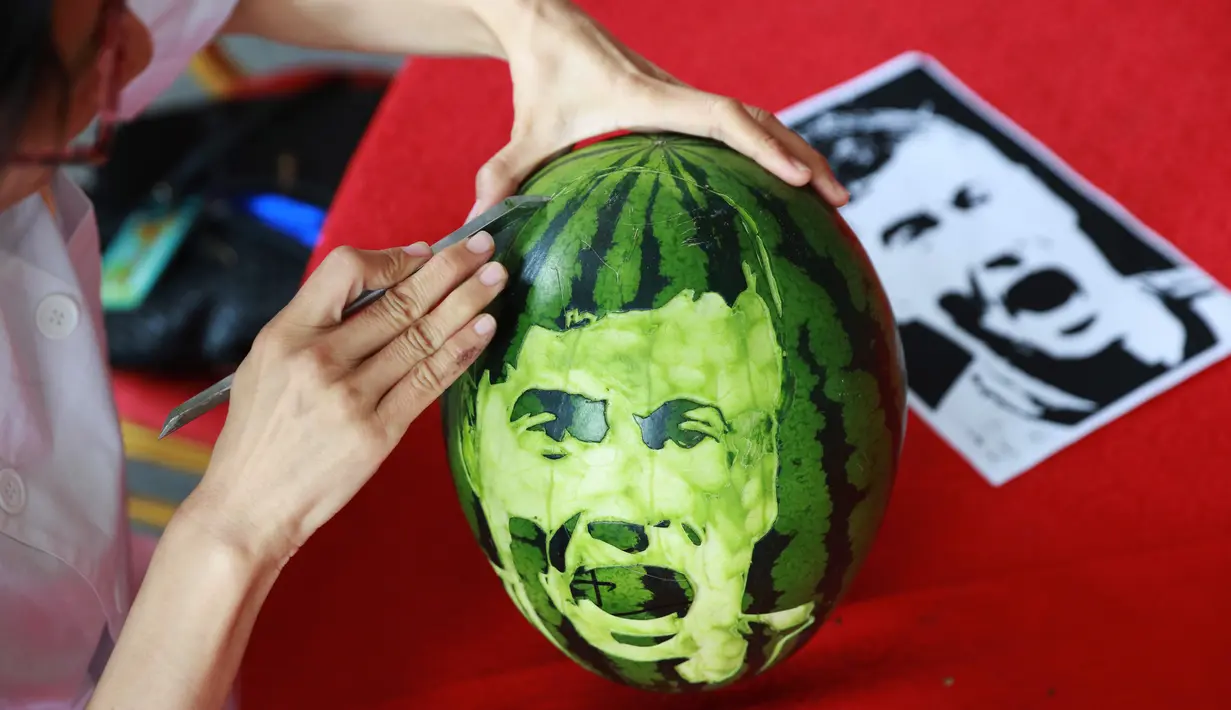Seorang siswa sekolah menengah mengukir wajah pemain sepak bola Polandia, Robert Lewandowski pada buah semangka di Shenyang, Provinsi Liaoning, China, Senin (9/7). (AFP)