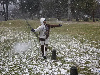 Gabriel Sussman bermain salju turun di taman Zoo Lake di Johannesburg, Afrika Selatan pada 10 Juli 2023. (Wikus de Wet / AFP)