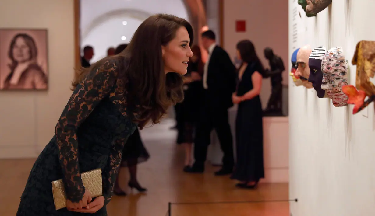 Kate Middleton melihat karya seni saat pameran Portrait Gala 2017 dan penggalangan dana di National Portrait Gallery, London (28/3). Kate Middleton tampil anggun mengenakan gaun berwarna hijau.  (Neil Hall/Pool photo via AP)