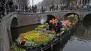 Orang-orang menunggu di jembatan untuk mendapatkan karangan bunga tulip gratis di Amsterdam, Belanda, Sabtu (15/1/2022). Toko-toko di seluruh Belanda dengan hati-hati dibuka kembali setelah berminggu-minggu penguncian virus corona. (AP Photo/Peter Dejong)