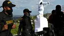 Petugas polisi anti huru hara menjaga patung penakluk Spanyol abad ke-16 Sebastian de Belalcazar yang ditutupi kain putih  di Cali, Kolombia (21/9/2020).  Patung Sebastian de Belalcazar telah berdiri di atas Popayan, sebuah kota di Kolombia, sejak 1937. (AFP/Luis Robayo)