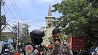 Petugas polisi berjaga di dekat sebuah gereja tempat ledakan meledak di Makassar, Sulawesi Selatan, Minggu (28/3/2021). Saat ini, akses di kawasan Katedral Makssar dibatasi. Pihak kepolisian masih berjaga-jaga di lokasi. (AP Photo/Yusuf Wahil)