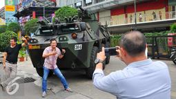 Sejumlah warga melakukan selfie dengan latar belakang Panser Anoa milik TNI di LTC Glodok, Jakarta, Jumat (4/11). Pengamanan ini merupakan bentuk kerja sama antara TNI-Polri dalam menjaga keamanan terkait demo bela islam . (Liputan6.com/Angga Yuniar)