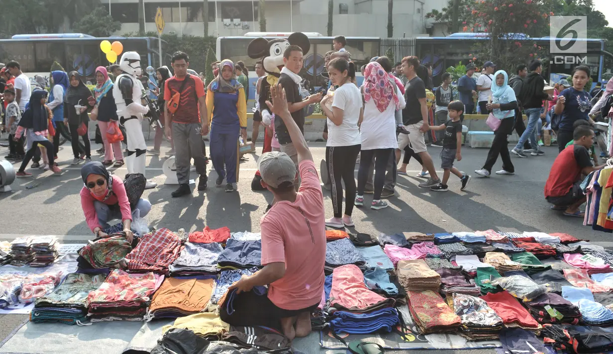 Warga melintasi lapak PKL saat car free day di MH Thamrin, Jakarta, Minggu (8/9/2019). Penutupan sebagian jalan akibat proyek revitalisasi trotoar membuat para PKL menggelar lapak hingga ke badan jalan sehingga menyebabkan aktivitas olahraga warga terhambat. (merdeka.com/Iqbal S. Nugroho)
