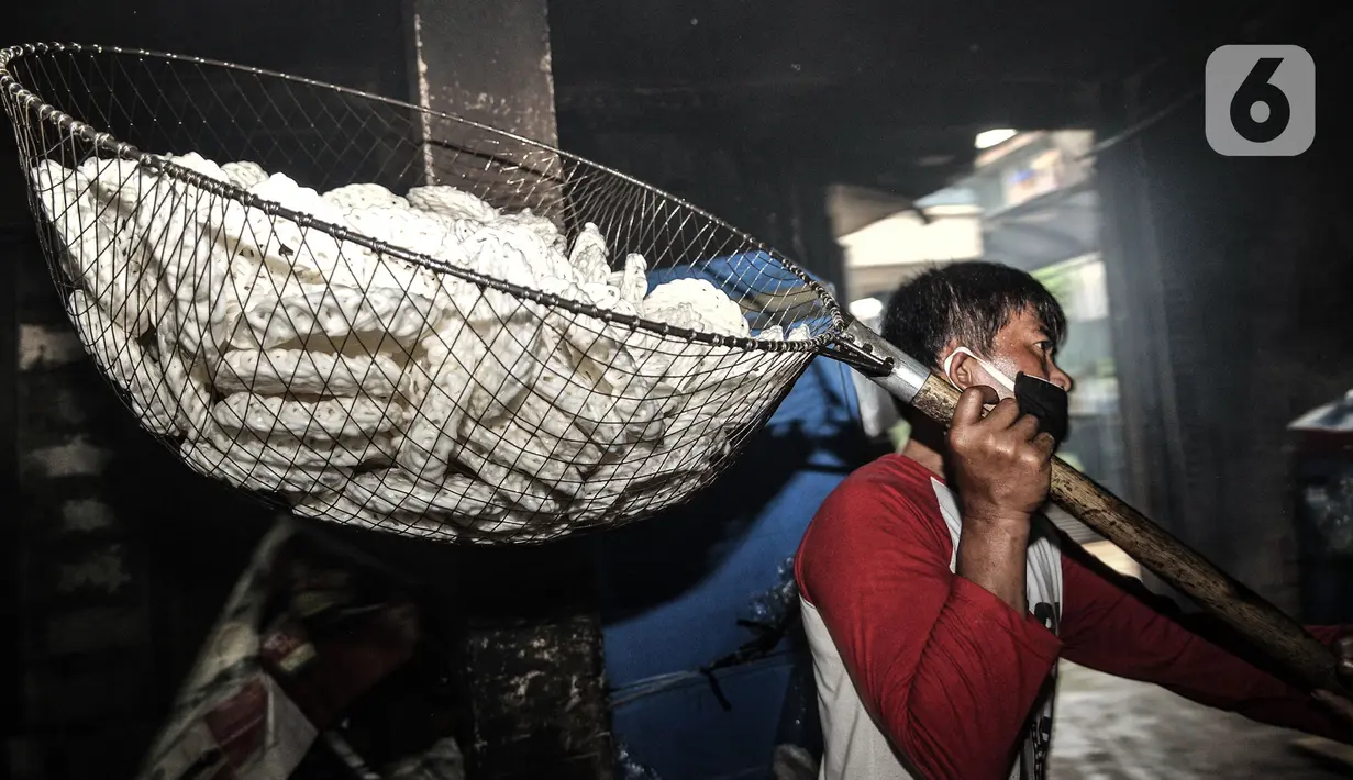 Pekerja mengangkut kerupuk yang telah digoreng di industri rumahan kawasan Cipinang Melayu, Jakarta, Selasa (16/2/2021). Selama pandemi corona, jumlah produksi di industri rumahan ini dikurangi dari 10.000 kerupuk per hari, kini hanya 5.000 kerupuk tiap harinya. (merdeka.com/Iqbal S Nugroho)