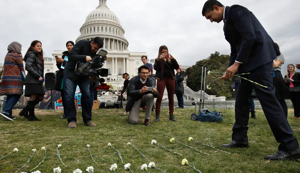 Rep. Ro Khanna, D-Calif meletakkan bunga di halaman rumput Gedung Capitol (kantor kongres) AS, Senin (19/3). 5000 bunga diletakkan untuk mengenang ribuan anak yang tewas akibat pengeboman oleh koalisi pimpinan Arab Saudi di Yaman. (AP/Jacquelyn Martin)