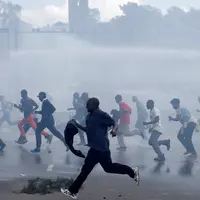 Pengunjuk rasa berlari menghindari gas air mata yang disemprotkan petugas saat bentrok di Nairobi, Kenya (16/5/2016). Mereka menuntut pembubaran otoritas pemilu karena adanya dugaan korupsi. (REUTERS/Goran Tomasevic)