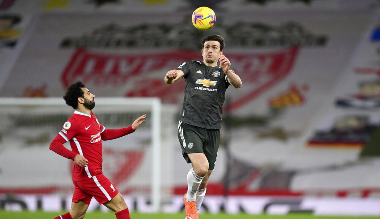 Bek Manchester United, Harry Maguire, berebut bola dengan pemain Liverpool, Mohamed Salah, pada laga Liga Inggris di Stadion Anfield, Minggu (17/1/2021). Kedua tim bermain imbang 0-0. (Michael Regan/Pool via AP)