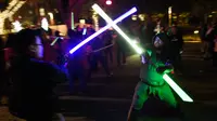 Dua orang pria saling beradu lightsaber (pedang sinar) saat mengikuti Glow Battle Tour di Grand Park, Los Angeles (15/12). Para penggemar ini berkumpul dengan membawa pedang sinar yang beraneka warna. (Photo by Chris Pizzello/Invision/AP)