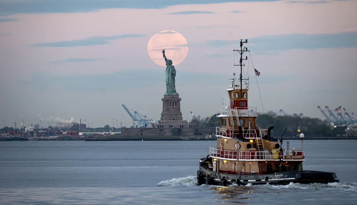 <p>Bulan purnama terlihat di belakang Patung Liberty, New York City, Amerika Serikat, Kamis (7/5/2020). Fenomena supermoon atau di belahan Bumi lain disebut flower moon ini merupakan yang terakhir di tahun 2020. (Johannes EISELE/AFP)</p>