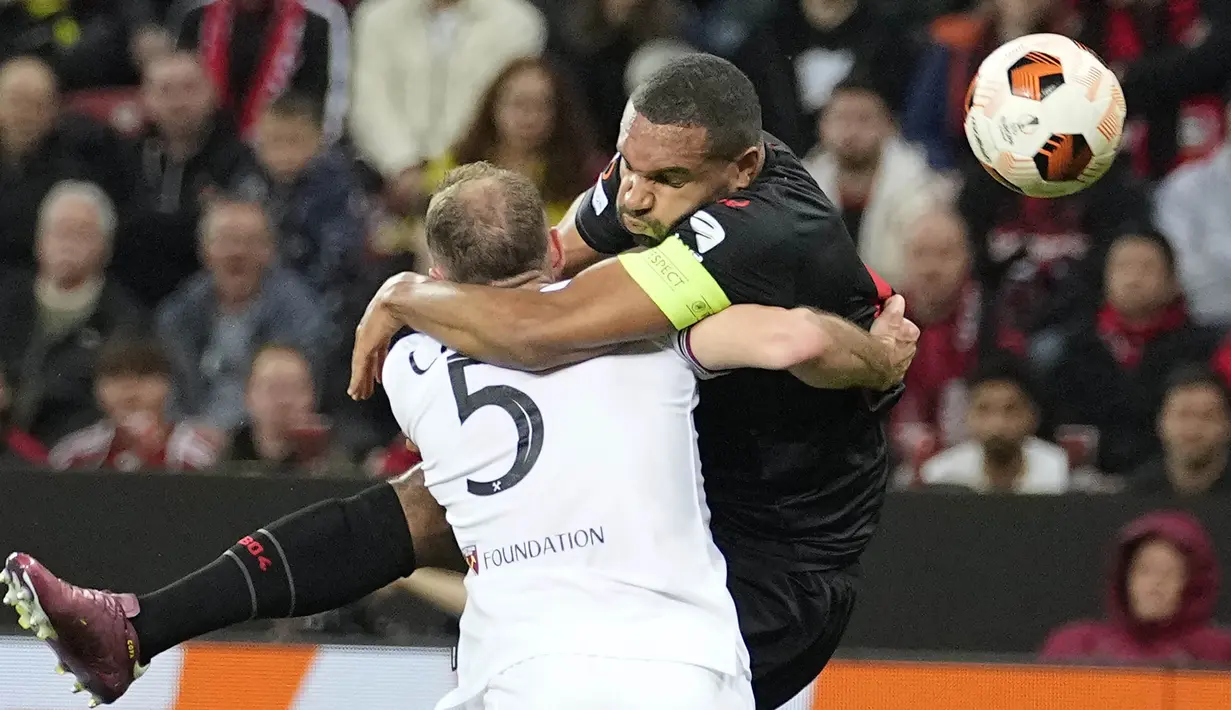 Pemain Bayer Leverkusen, Jonathan Tah, berebut bola dengan pemain West Ham United, Vladimir Coufal, pada laga Perempat final Liga Europa di Stadion BayArena, Jumat (12/4/2024). (AP Photo/Martin Meissner)