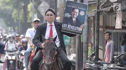 Motivator Tung Desem Waringin mempromosikan buku terbarunya berjudul 'Life Revolution' dengan berkuda di Jakarta, Kamis (7/6). Life Revolution merupakan buku ketiga yang dibuat Tung Desem Waringin. (Liputan6.com/Faizal Fanani)