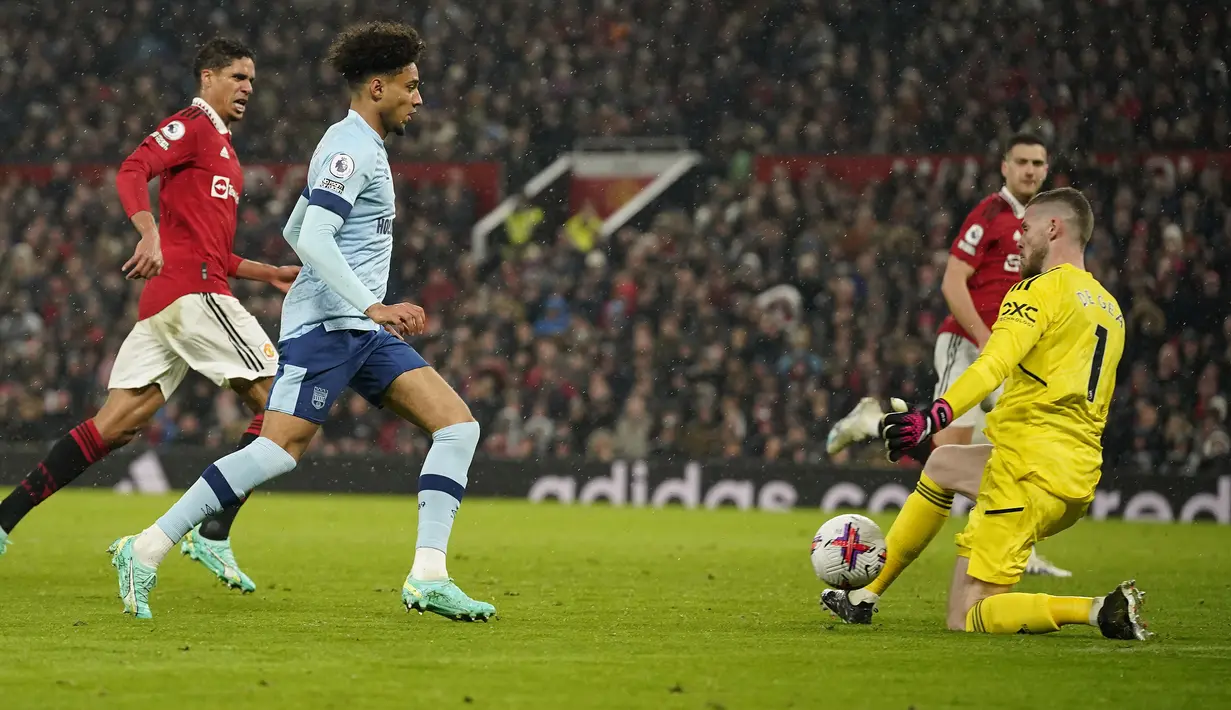 Kiper Manchester United, David De Gea (kanan) berhasil mementahkan tendangan yang dilepaskan gelandang Brentford, Kevin Schade pada laga lanjutan Liga Inggris 2022/2023 di Old Trafford Stadium, Manchester, Kamis (6/4/2023) dini hari WIB. (AP Photo/Dave Thompson)